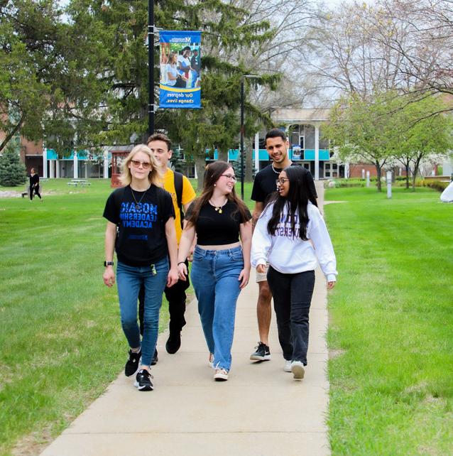 small group of five students walking along campus exterior walkway 